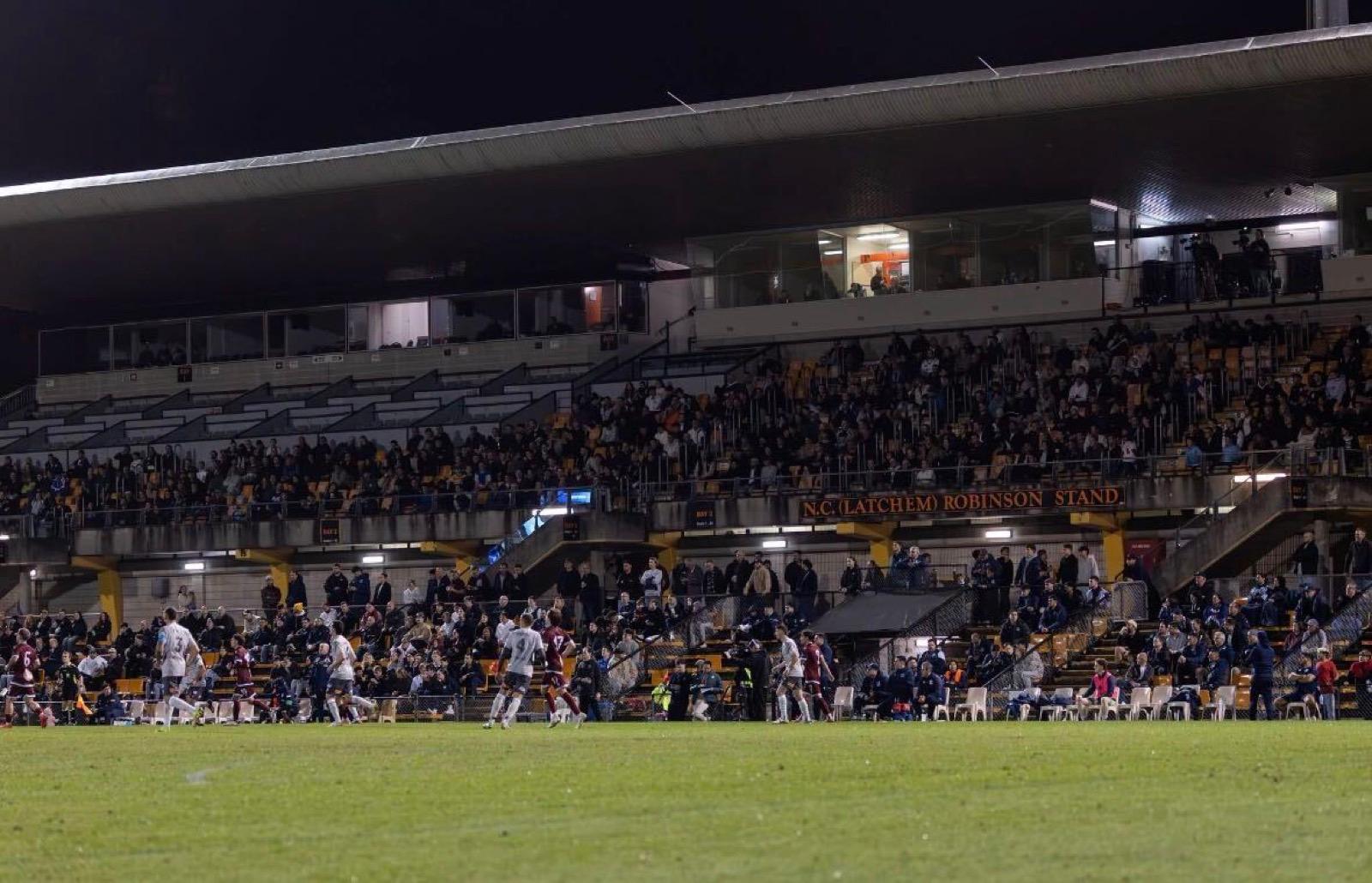 Grandstand crowd at a floodlit night football match